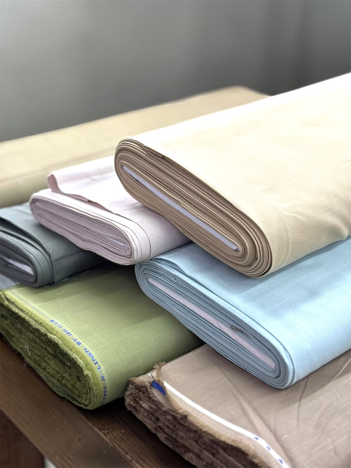 Folded bolts of premium linen and cotton shirting fabric in pastel shades at the Jagdamba Fabrics mill