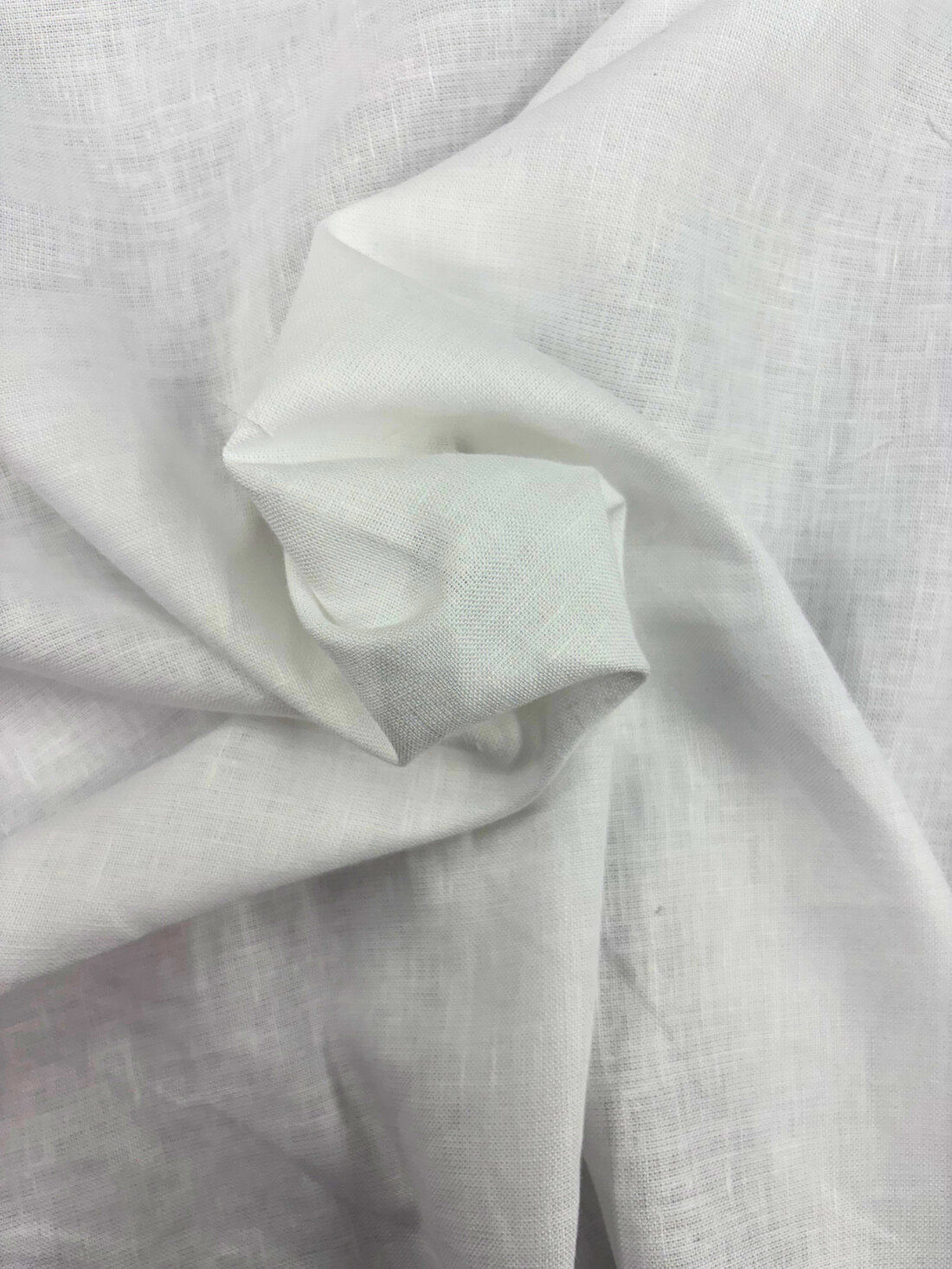 A close-up of cream linen fabric draping in window light.